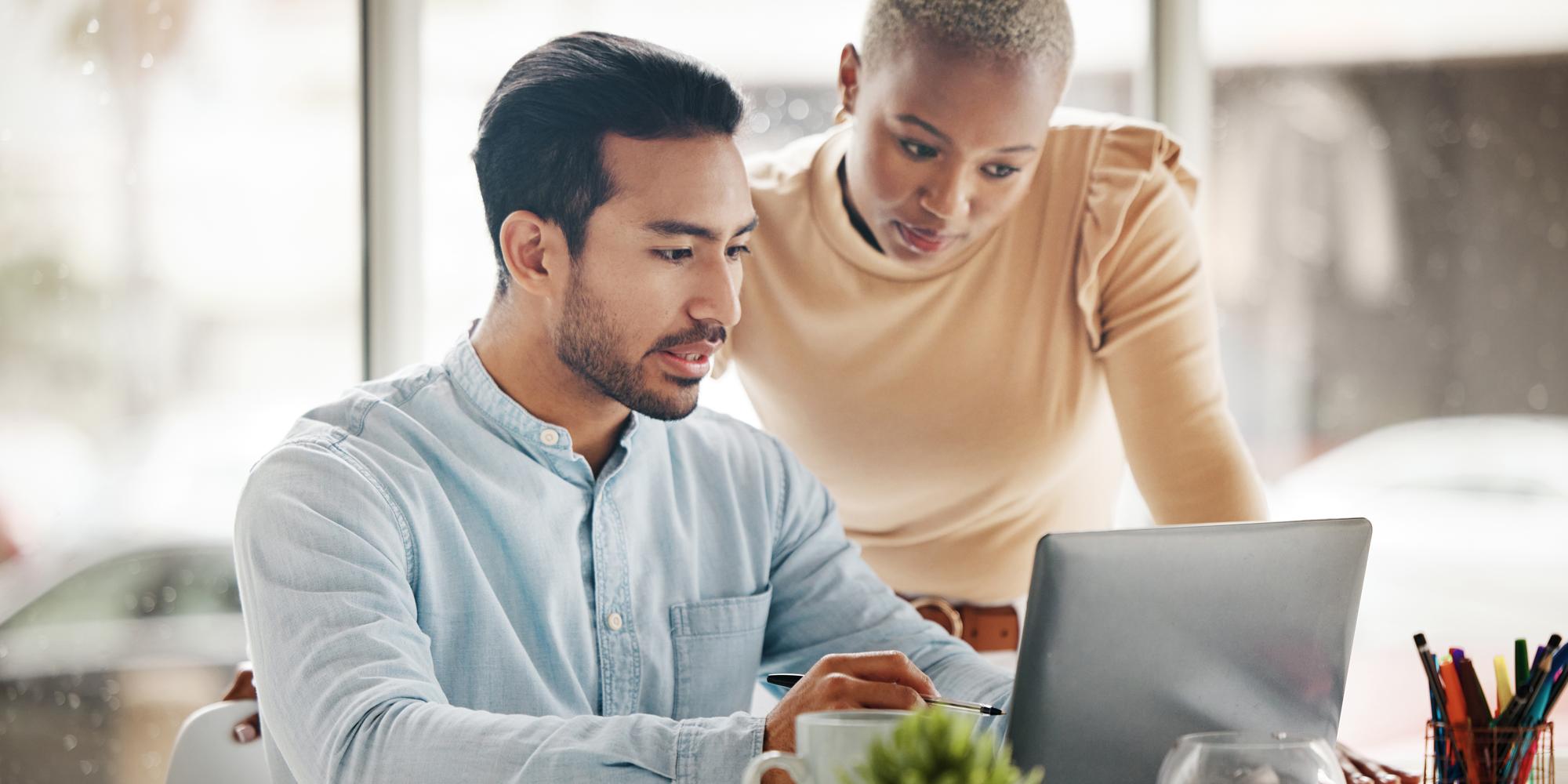 Two people looking at a laptop researching the advantages of using a low-code platform